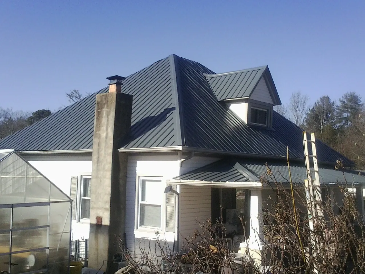 Dark blue standing seam metal roof on a white farmhouse with dormer — Slate & Tile Roof Repair by Roofing Brothers in Port Hadlock