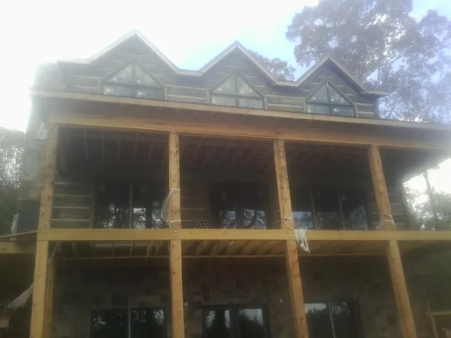 Dormers and porch framing on a large log home under construction — Roof Coating work by our crew in Port Hadlock