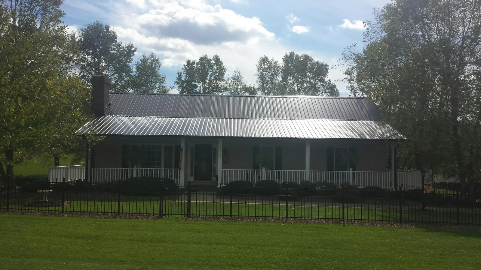Gray metal roof on a brick ranch with a full width front porch — Gutter Guard Installation work by our crew in Port Hadlock