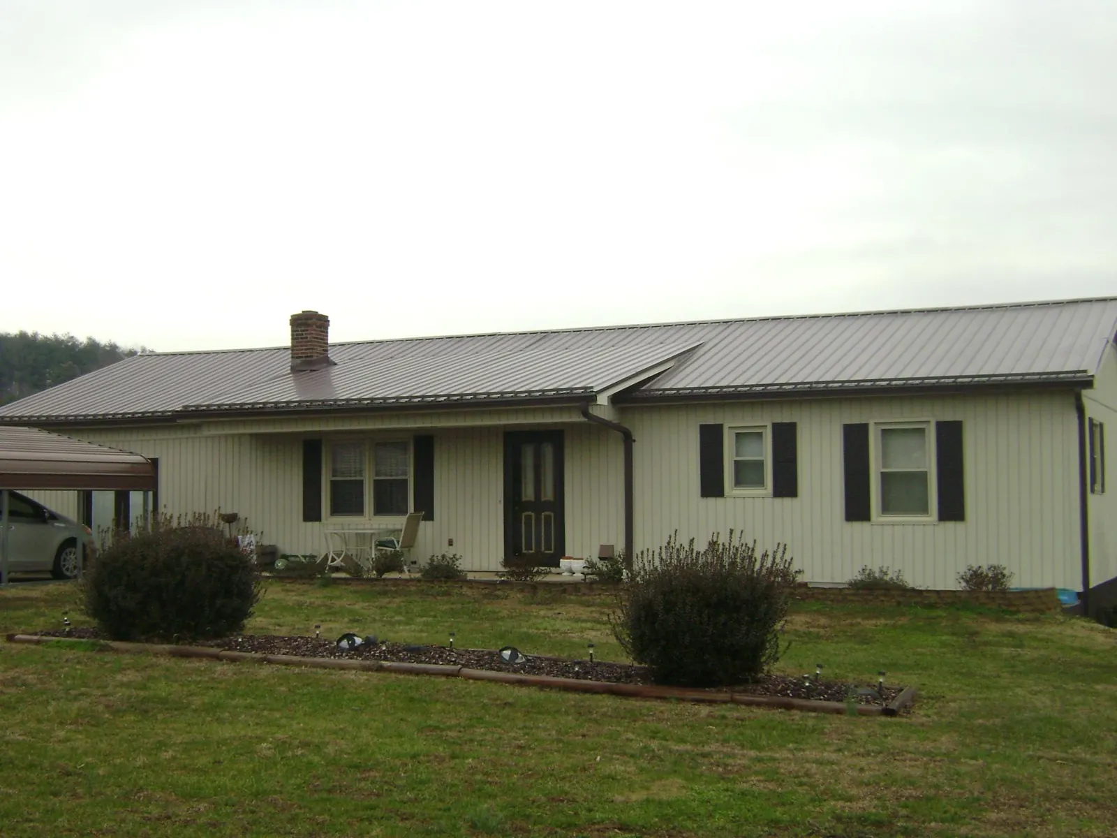 Brown metal roof on a cream sided ranch home with a brick chimney in Port Hadlock