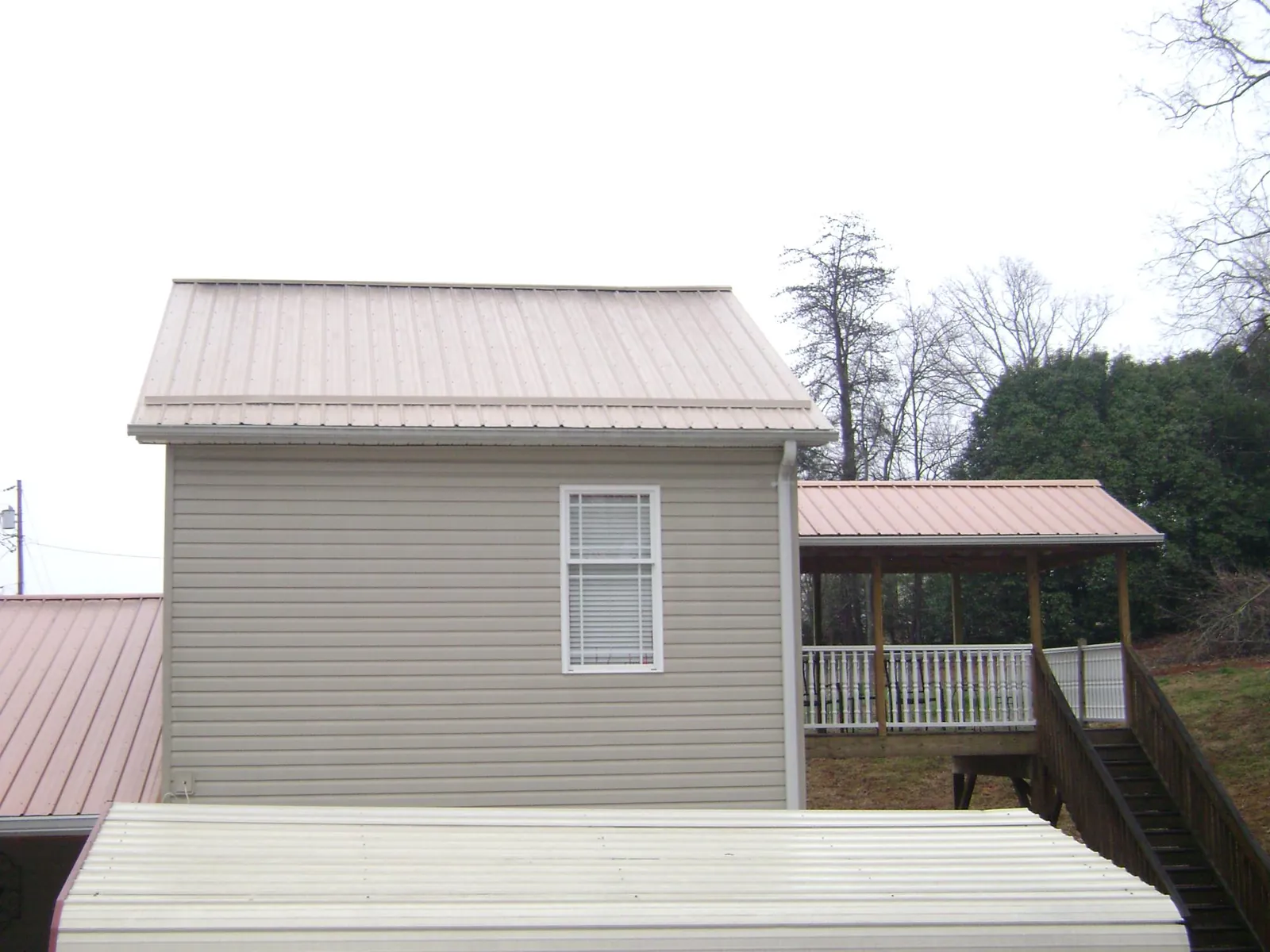 Tan metal roofs on a two story addition and attached porch, from a Roof Replacement job in Port Hadlock