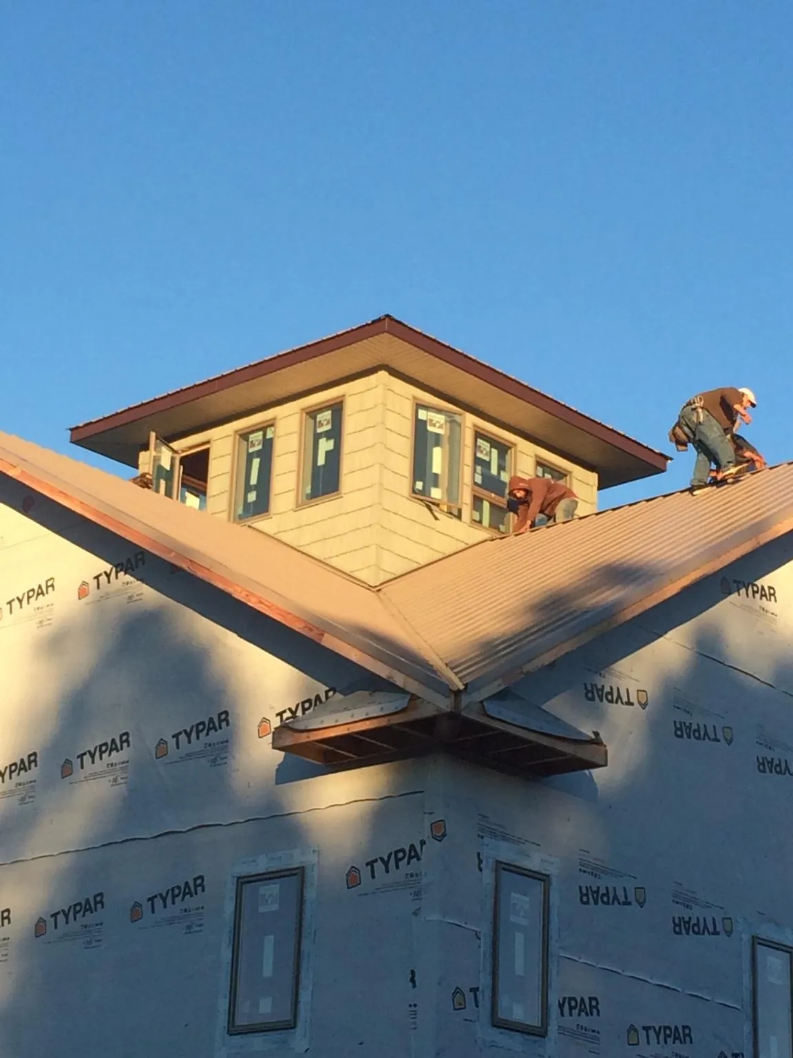 Roofers working around a rooftop cupola on a new metal roof at sunset — Roof Waterproofing in Port Hadlock by Roofing Brothers
